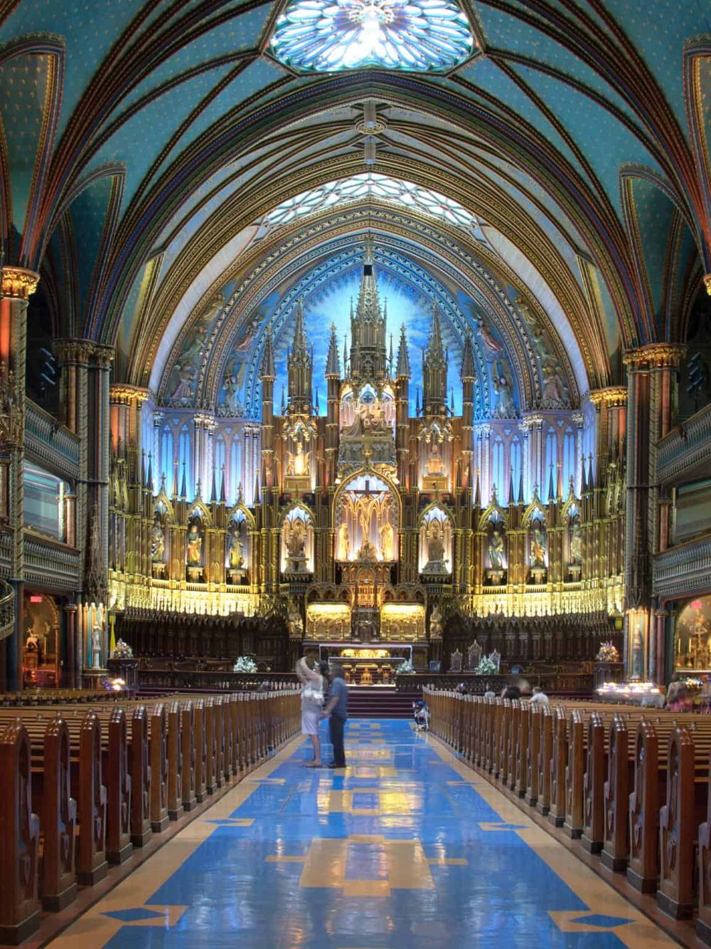 Colorful gothic cathedral interior with ornate architecture and vibrant lighting, showcasing religious art and stained glass windows.