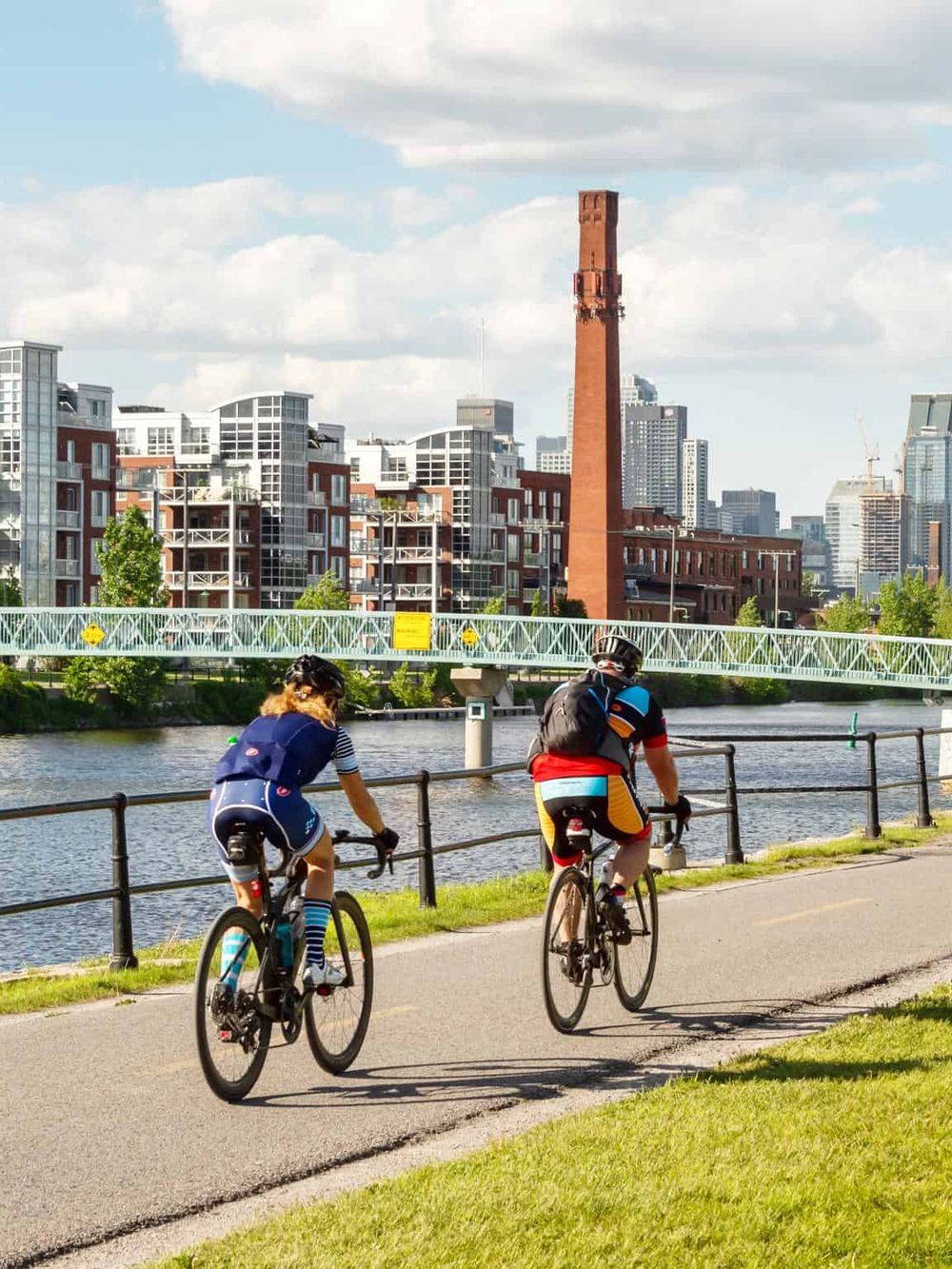 Bike riders enjoying a scenic path along the river with city skyline in background in quest for directions.