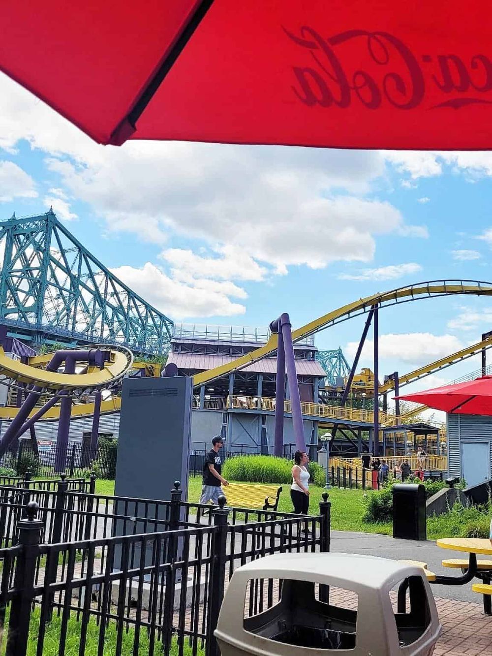 Colorful amusement park with roller coaster rides and visitors enjoying sunny weather.