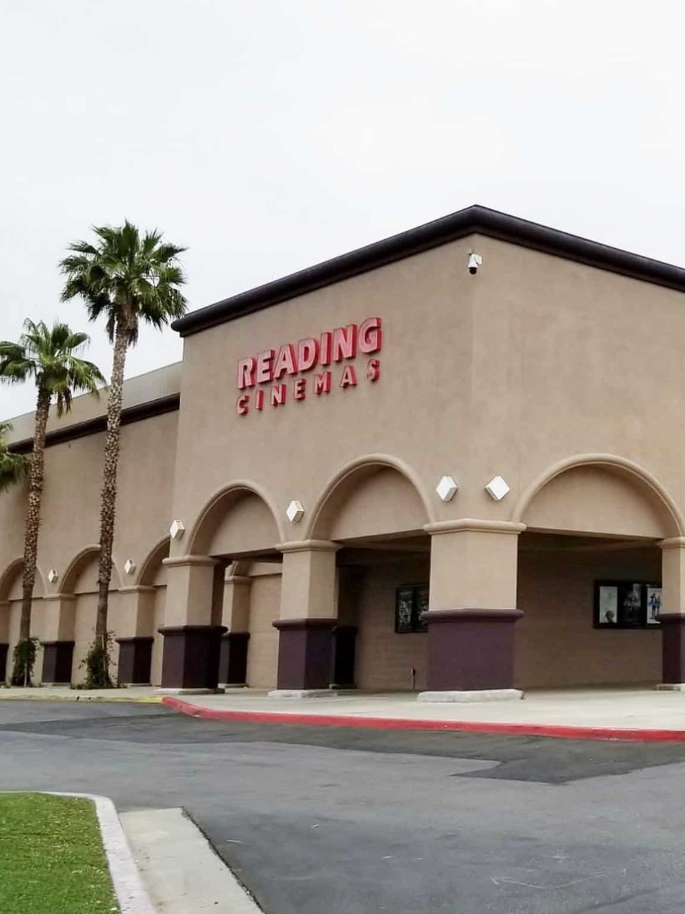Brightly lit Reading Cinemas theater with palm trees in front, perfect for movie night.