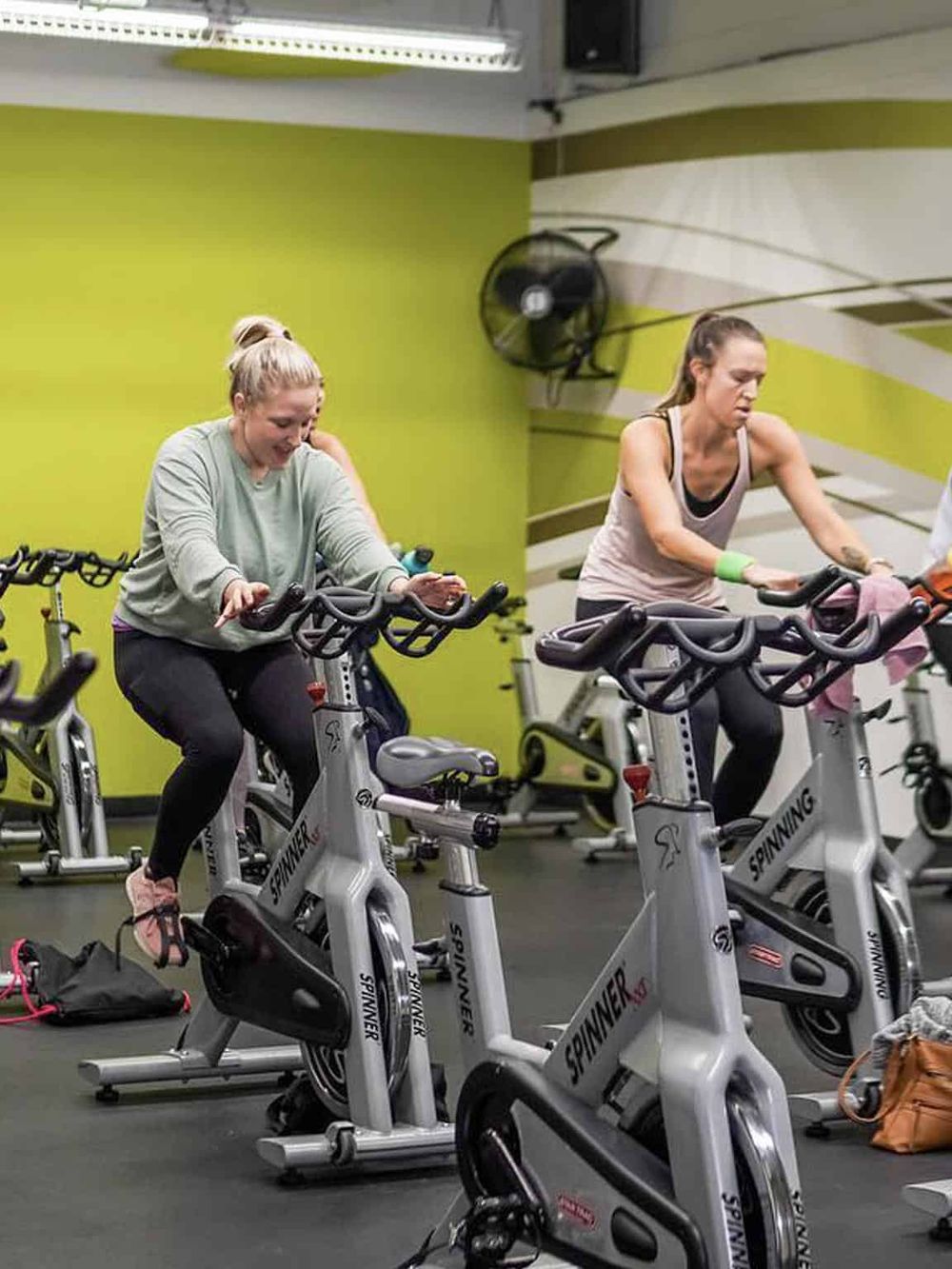 1. Women exercising on spin bikes in a fitness class at Quest For Directions gym facility.