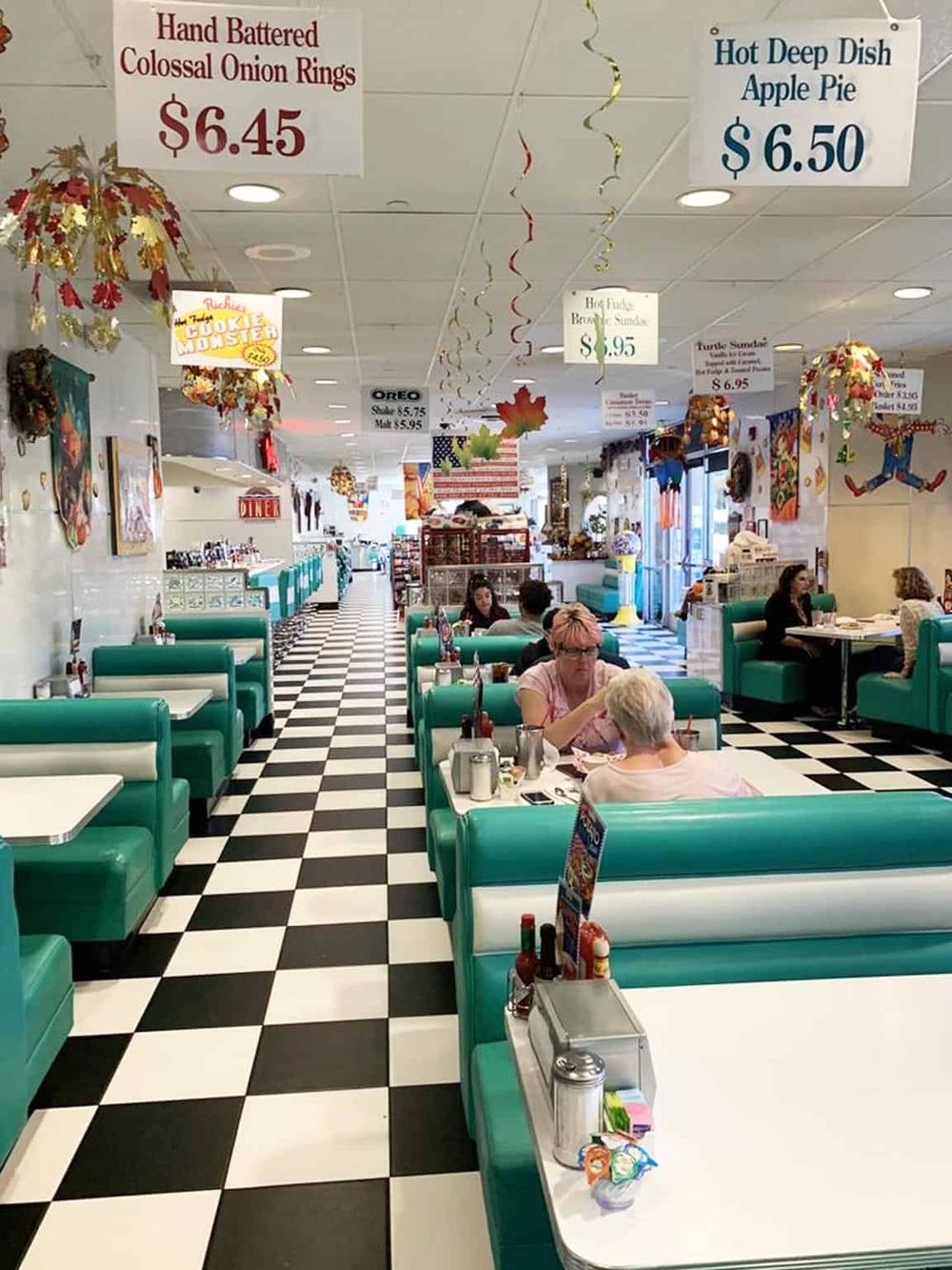 Colorful vintage American diner interior with turquoise booths and black-and-white checkered floor.