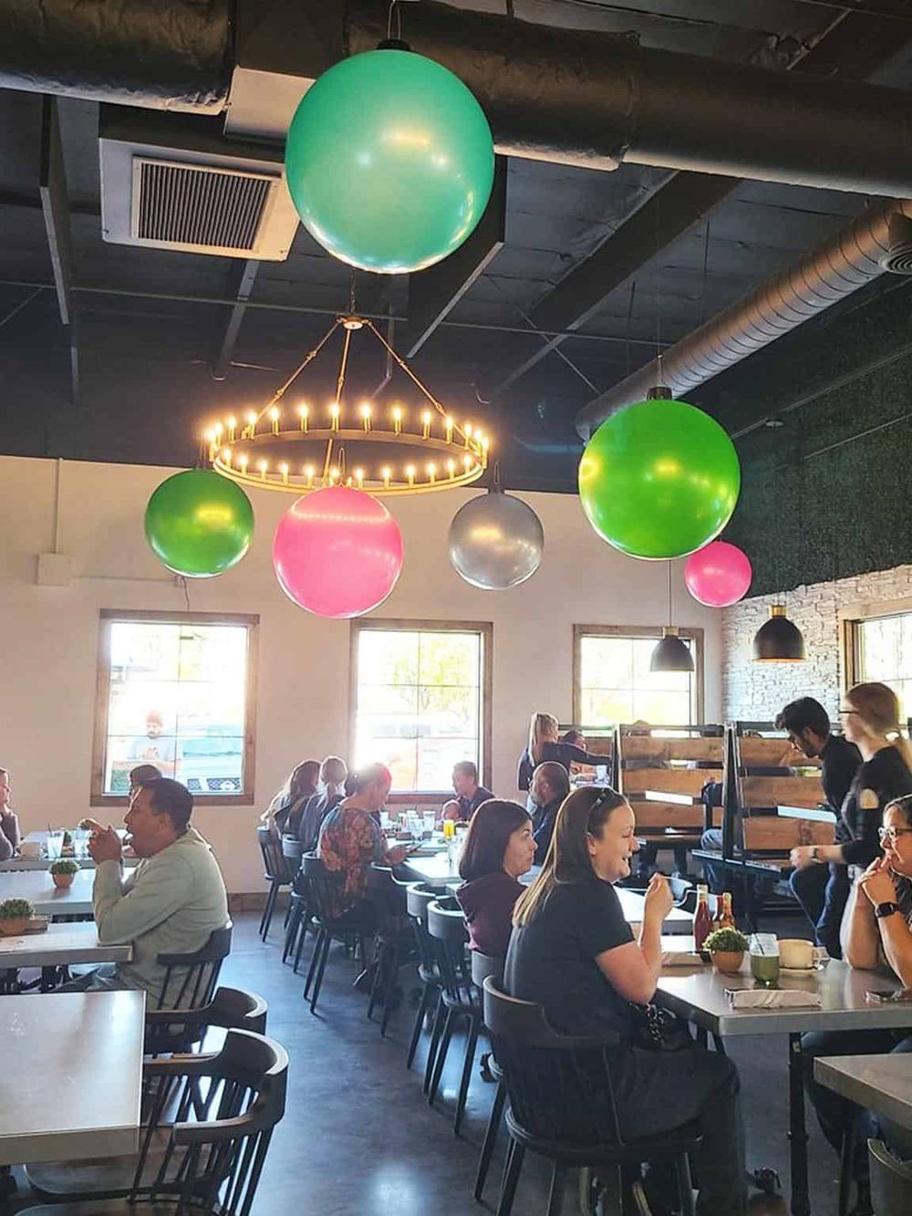 Colorful hanging light fixtures in a lively restaurant with diners, creating a vibrant and inviting atmosphere.