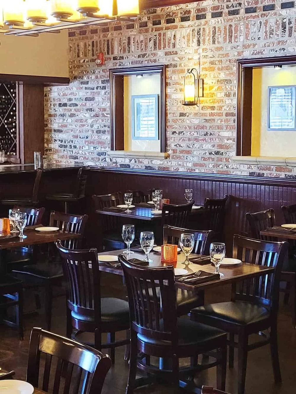 Warm, inviting restaurant interior with exposed brick walls and elegant table settings for dining.