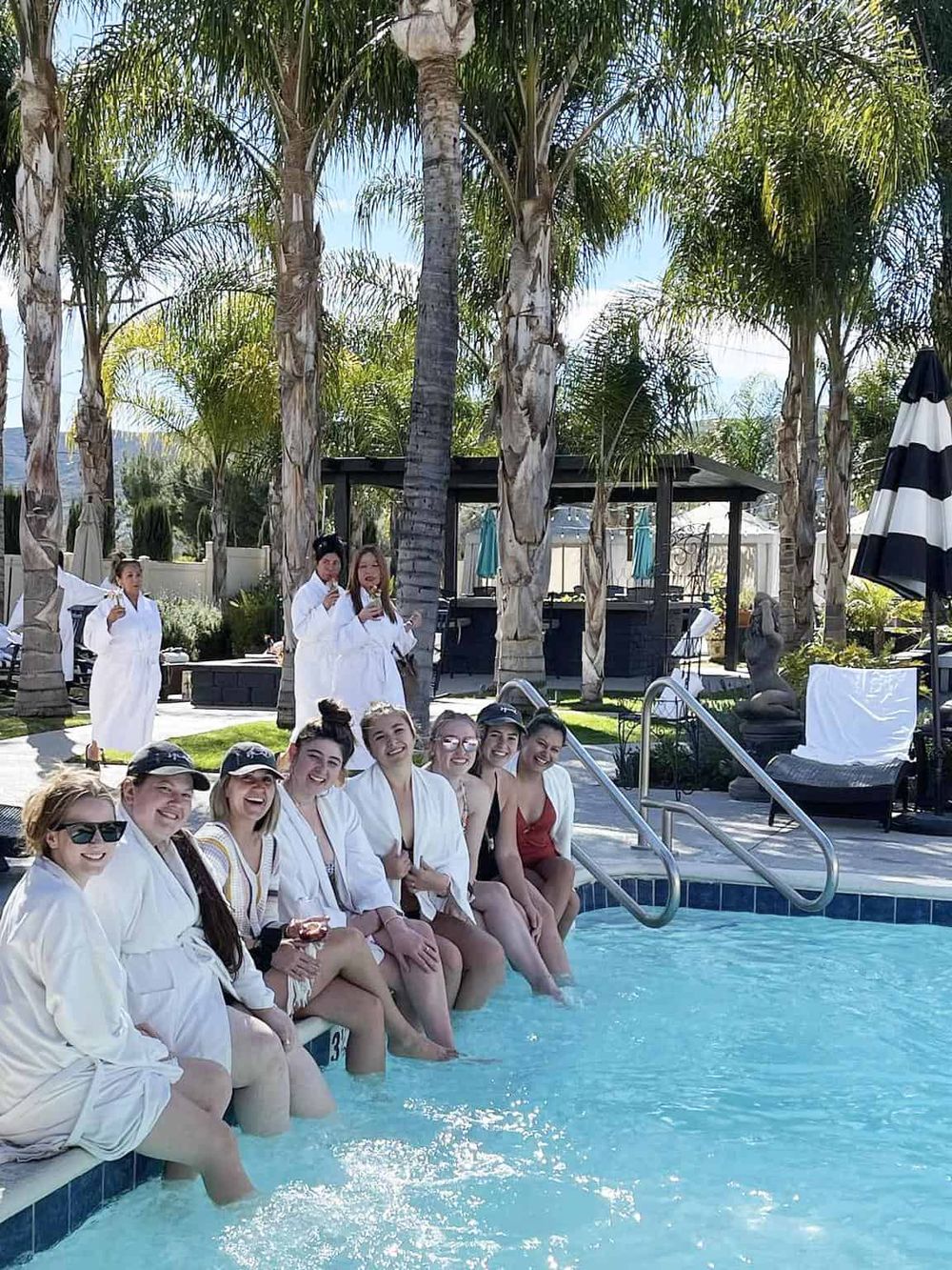 Relaxing poolside at a luxury resort with friends, surrounded by palm trees and outdoor amenities.