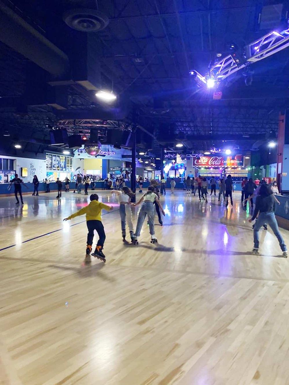 Indoor roller skating rink with kids skating under colorful neon lights. Fun family activity and entertainment center.