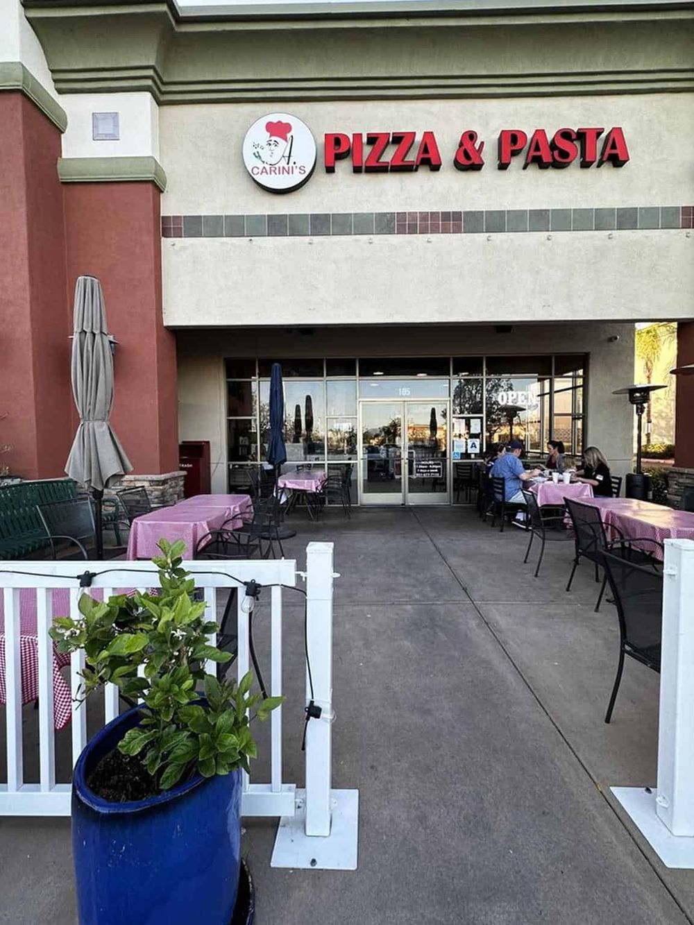 Fresh pizza and pasta restaurant with outdoor seating, pink tablecloths, and a welcoming dining area.