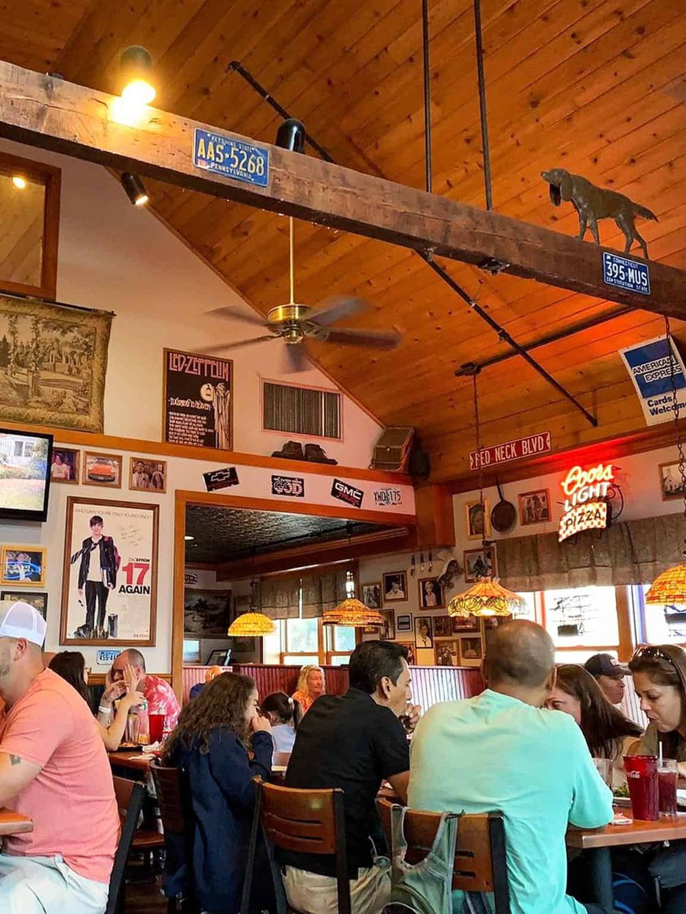 Cozy restaurant interior with wooden ceiling, vintage decor, and diners enjoying meals.