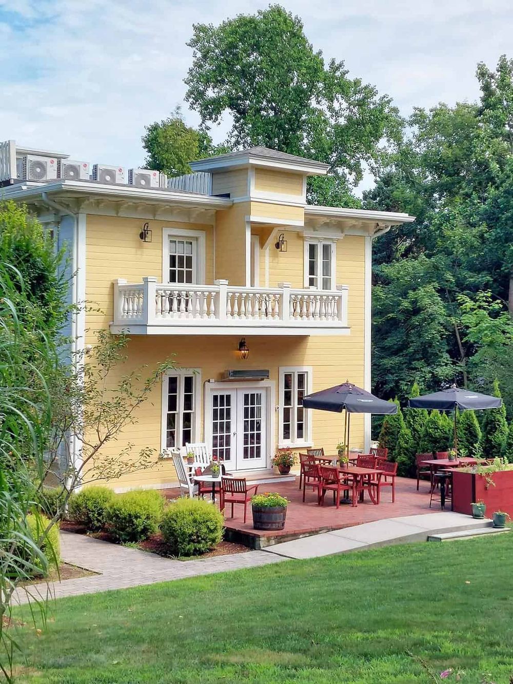Charming yellow house with outdoor patio, cozy seating, and vibrant greenery for your home improvement needs.