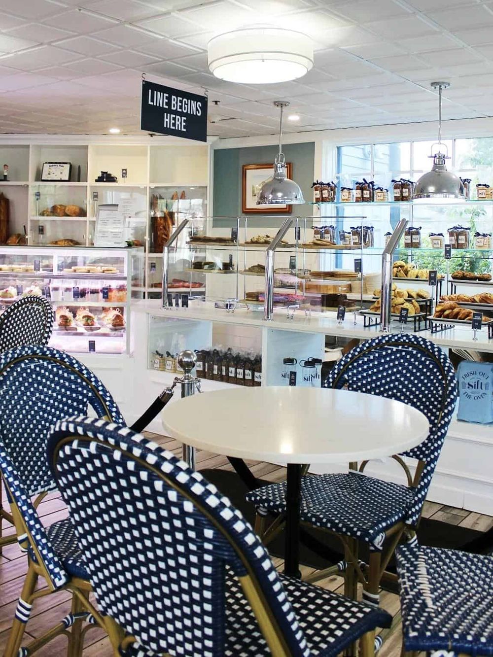 Fresh bakery and cafe interior with blue wicker chairs and display case, perfect for quick bites and coffee.