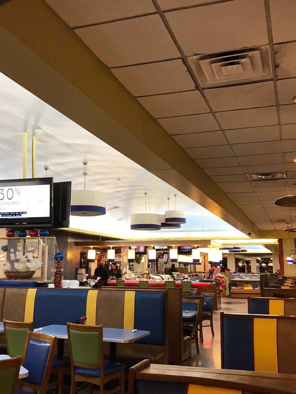 Bright indoor restaurant interior with colorful seating, modern lighting, and a buffet setup, ideal for family dining and casual gatherings.