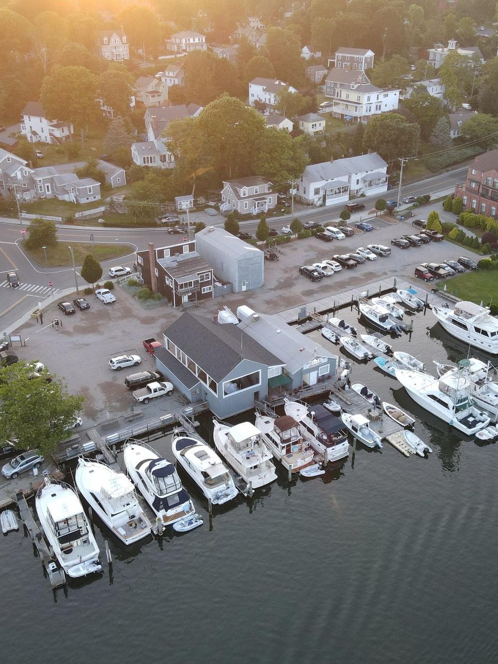 Marina with boats and waterfront houses at sunset, scenic harbor views, coastal residential neighborhood.