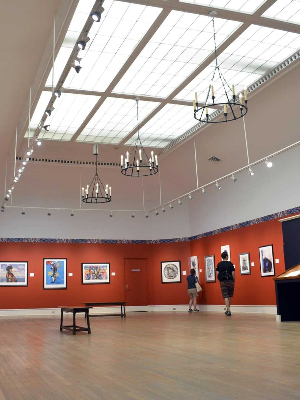 Bright art gallery interior with paintings, chandeliers, and skylight ceiling, showcasing QuestForDirections art exhibition.
