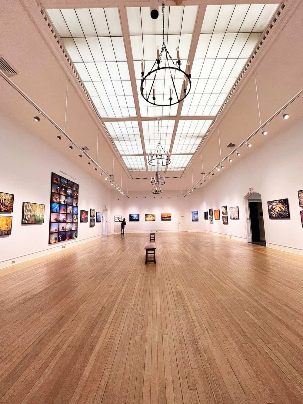 Bright art gallery interior with paintings, high ceiling, and chandeliers - QuestForDirections.