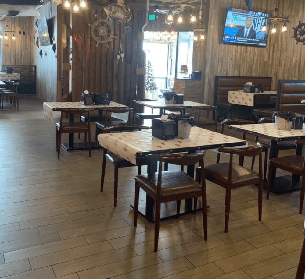 Cozy nautical-themed restaurant interior with wooden walls, ship steering wheel decor, and wall-mounted TV.