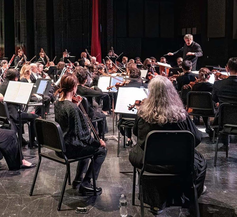 Orchestra performance with conductor on stage, showcasing classical music and live symphony in a concert hall.