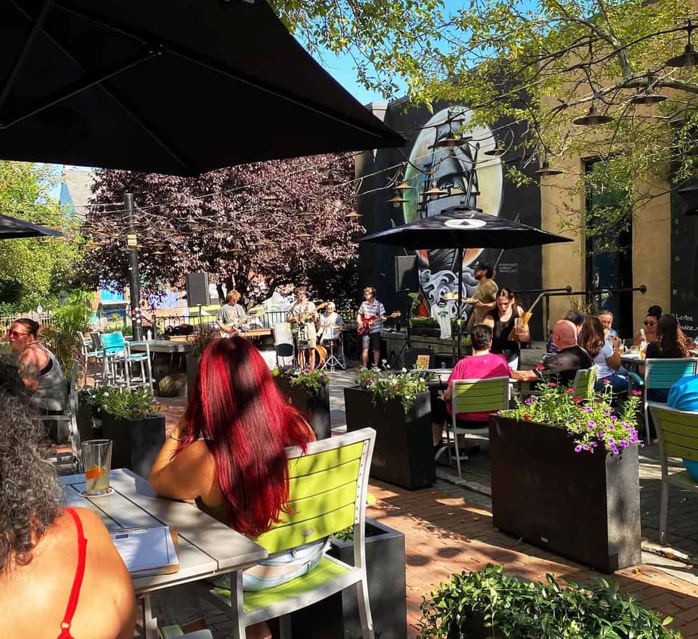 Relaxing outdoor cafe with live music, vibrant garden setting, and diverse crowd for a memorable dining experience.