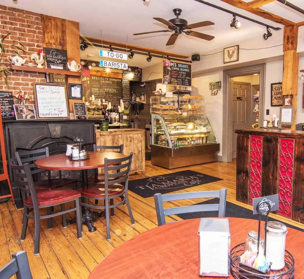 Cozy coffee shop interior with wooden accents, menu boards, and display case, perfect for a relaxing visit.