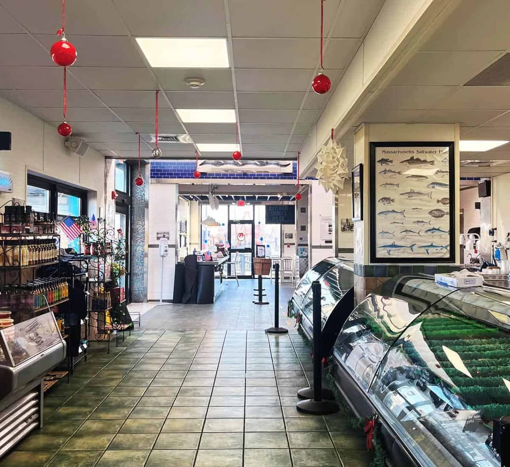 Bright seafood market interior with fish display cases and holiday decorations, including red ornaments and festive ornaments.