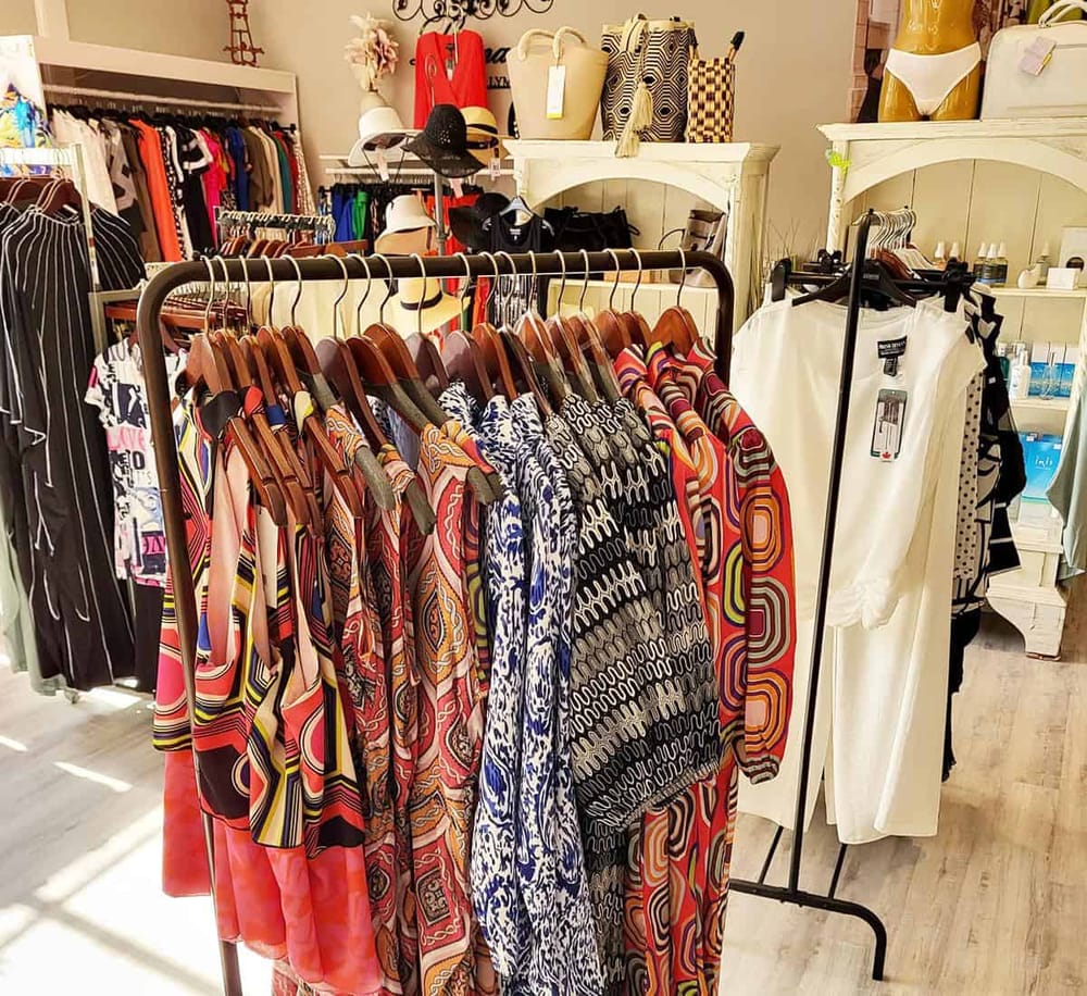 Vibrant patterned dresses on a clothing rack in a boutique retail store.