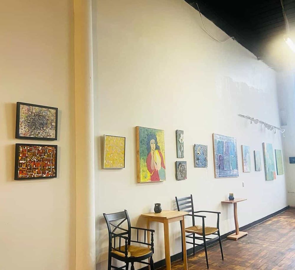Colorful art gallery interior with paintings, chairs, and small tables, ideal for creative artwork displays.