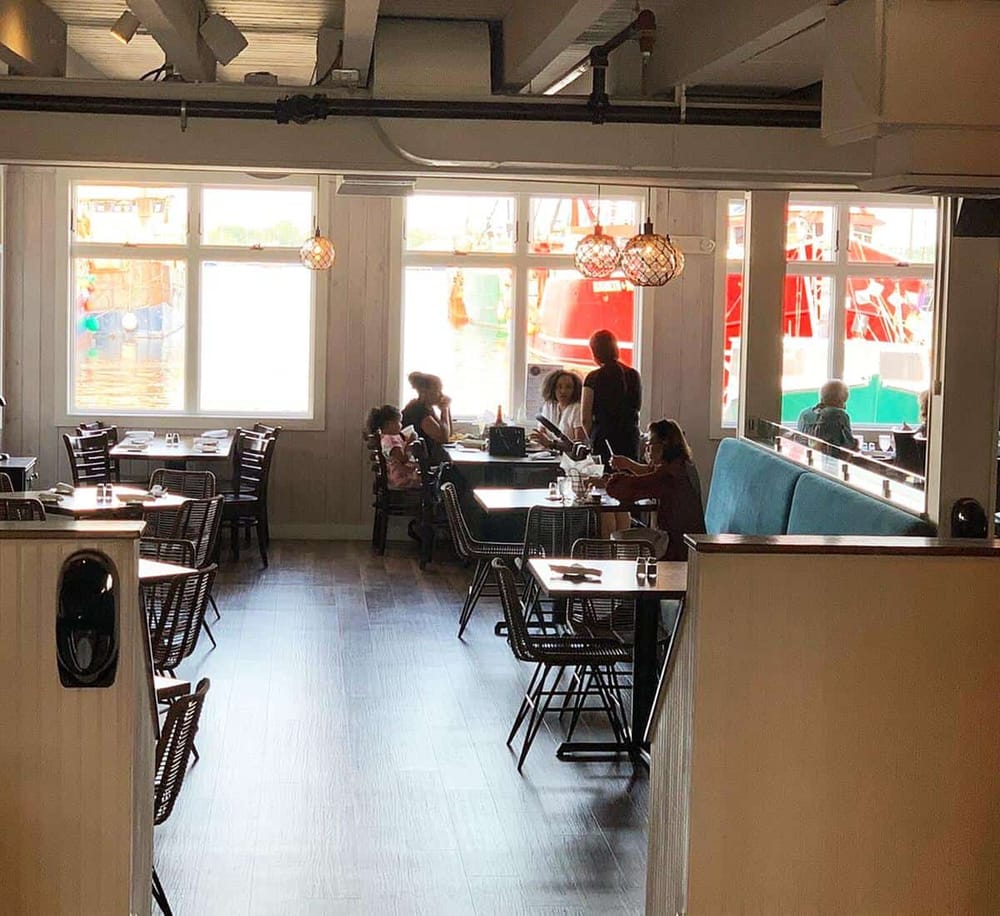 Cozy waterfront dining restaurant with large windows and nautical decor. Perfect for relaxing meals near the harbor.