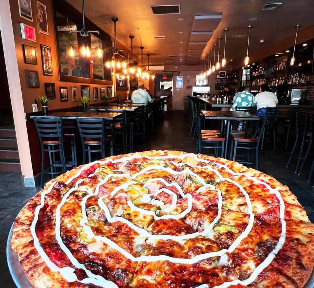 Delicious spiral pizza with toppings and drizzle in a cozy restaurant setting.