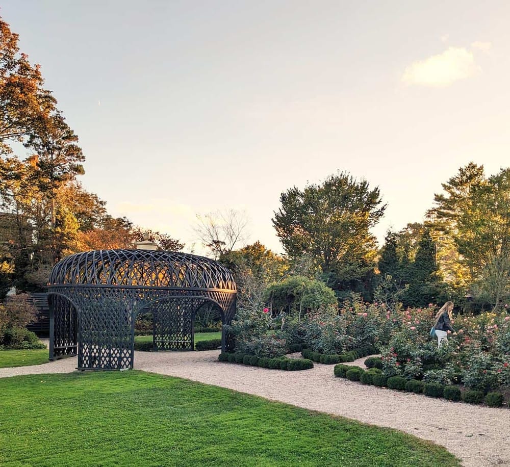 Versatile outdoor garden with gazebo, lush plants, and walking path in a serene park setting.