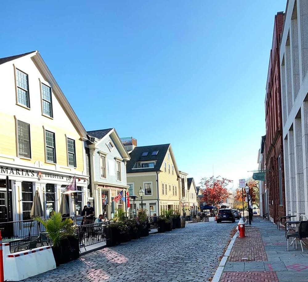 Charming street with colorful buildings, outdoor dining, and boutique shops, perfect for exploring local attractions and dining experiences.