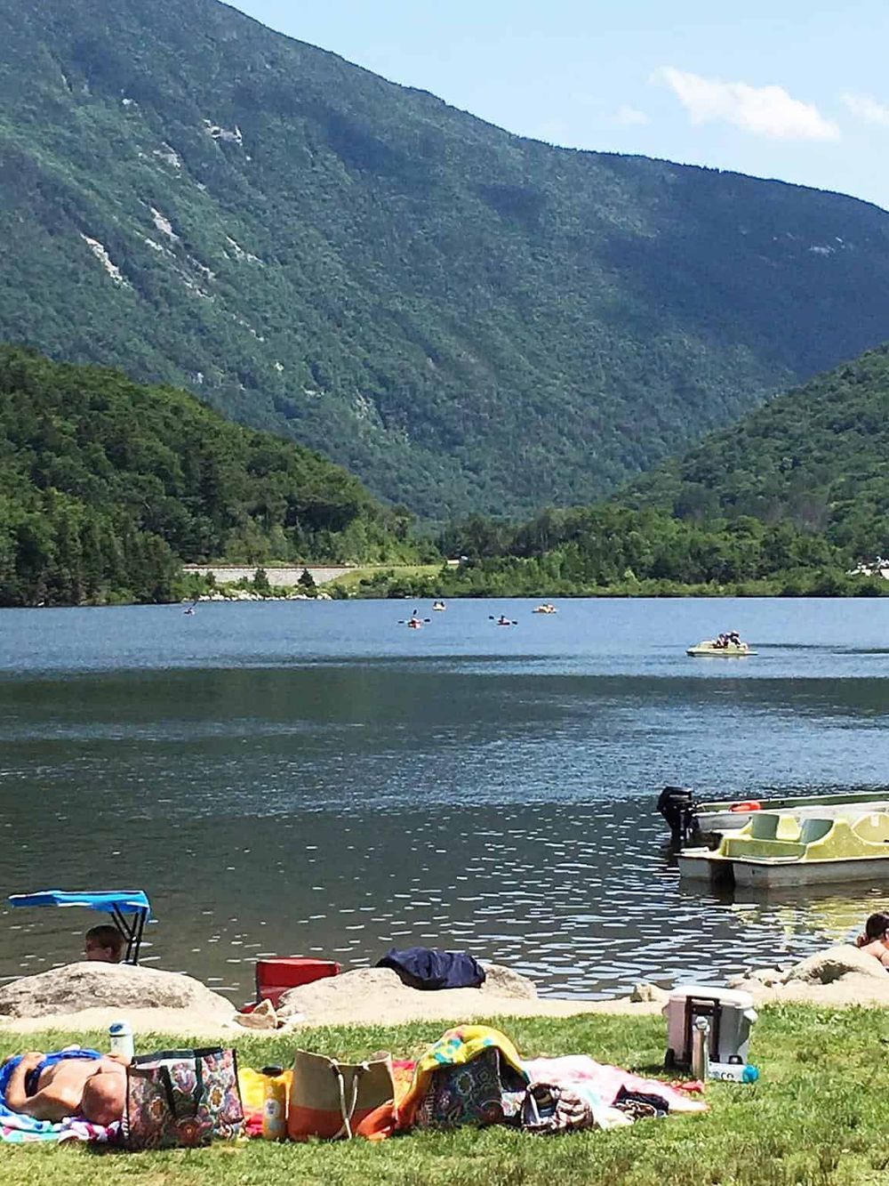 Serene mountain lake with boats and picnic area, perfect for outdoor recreation and nature getaways.
