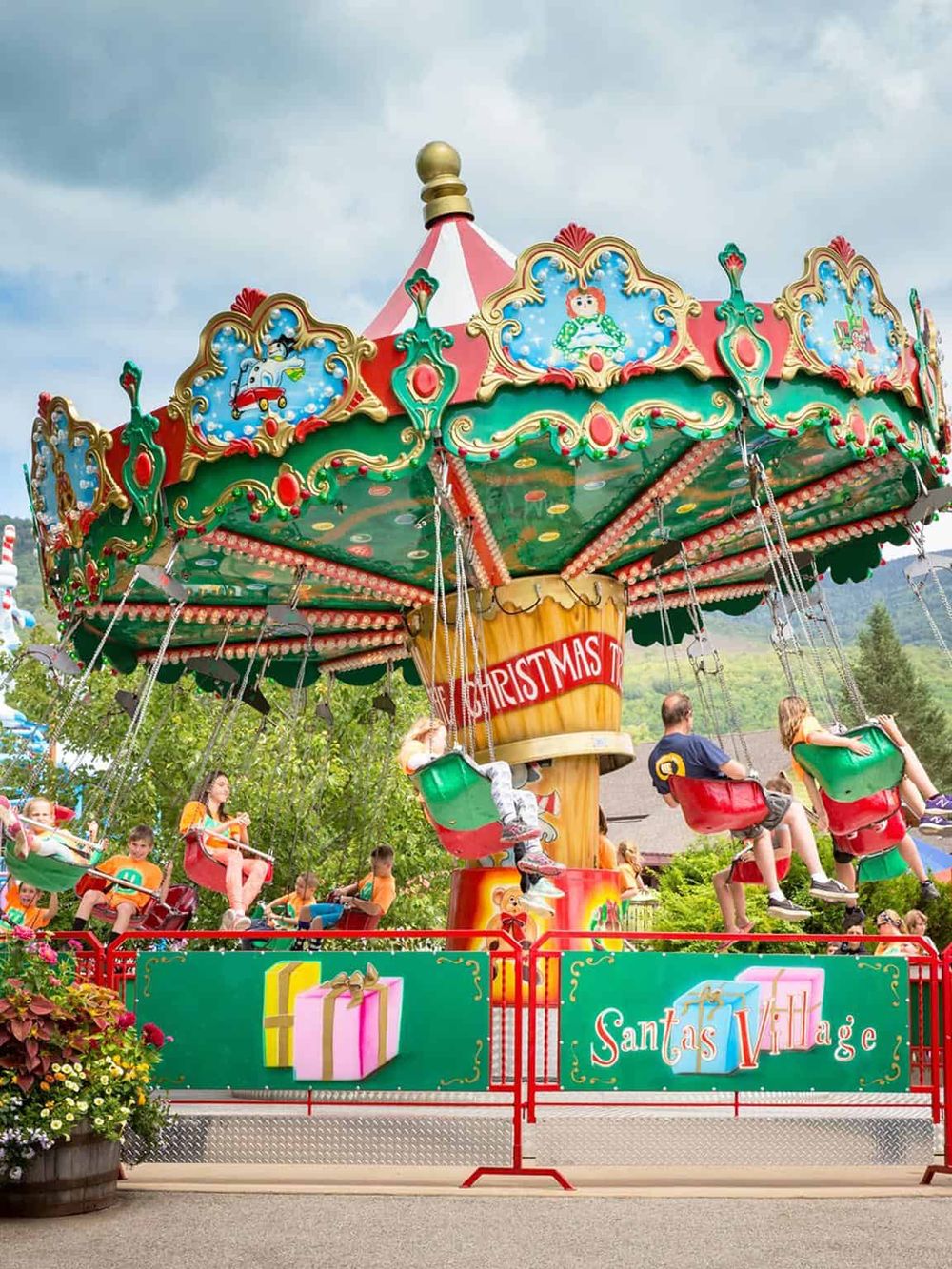 Colorful Christmas-themed amusement park ride with children enjoying swings.