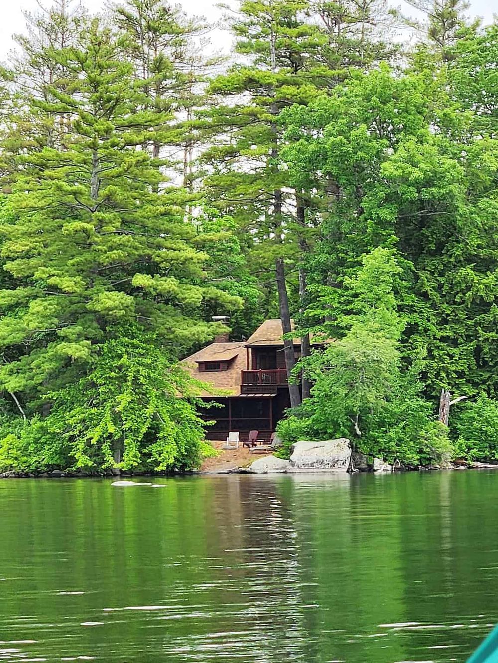 Secluded lakeside cabin surrounded by lush green trees, perfect for nature retreat and water activities.
