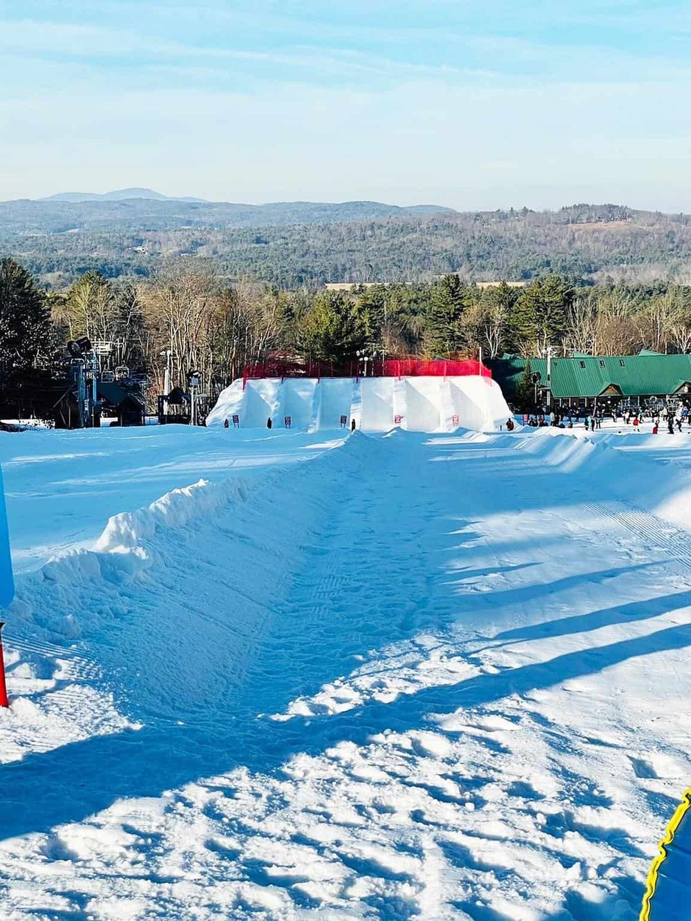Snow-covered ski slope with a large inflatable jump at Quest for Directions outdoor winter adventure park.