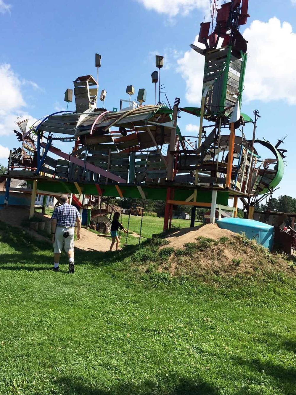 Colorful wooden playground structure with slides and swings in a park.