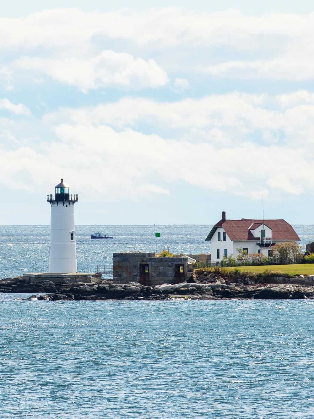 Lighthouse by the ocean with a house and boat, symbolizing navigation and travel assistance.