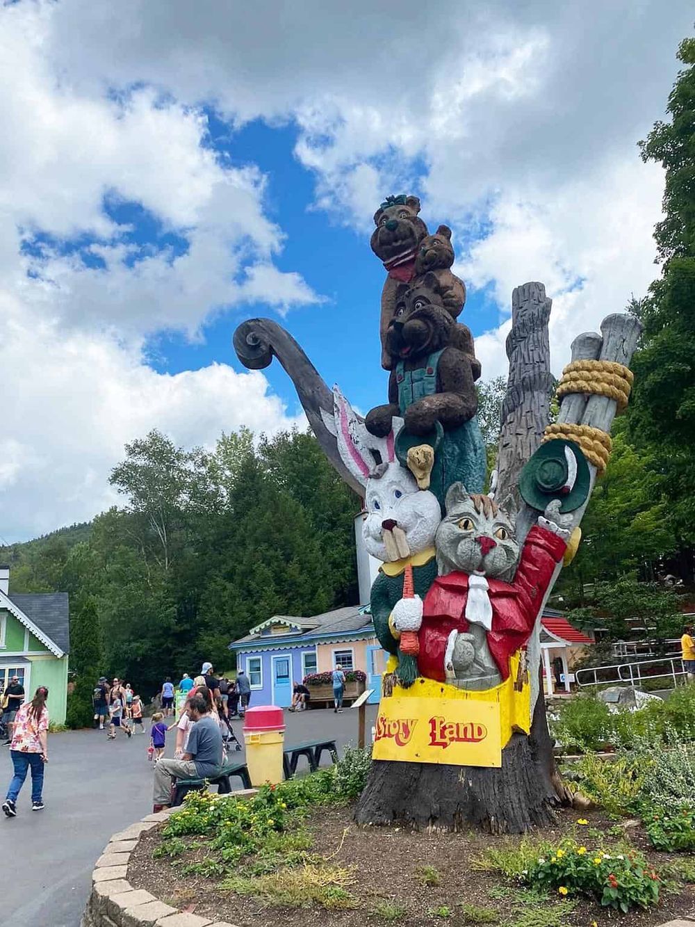 Colorful Story Land sculpture with cartoon animals and children at amusement park in bright outdoor setting.