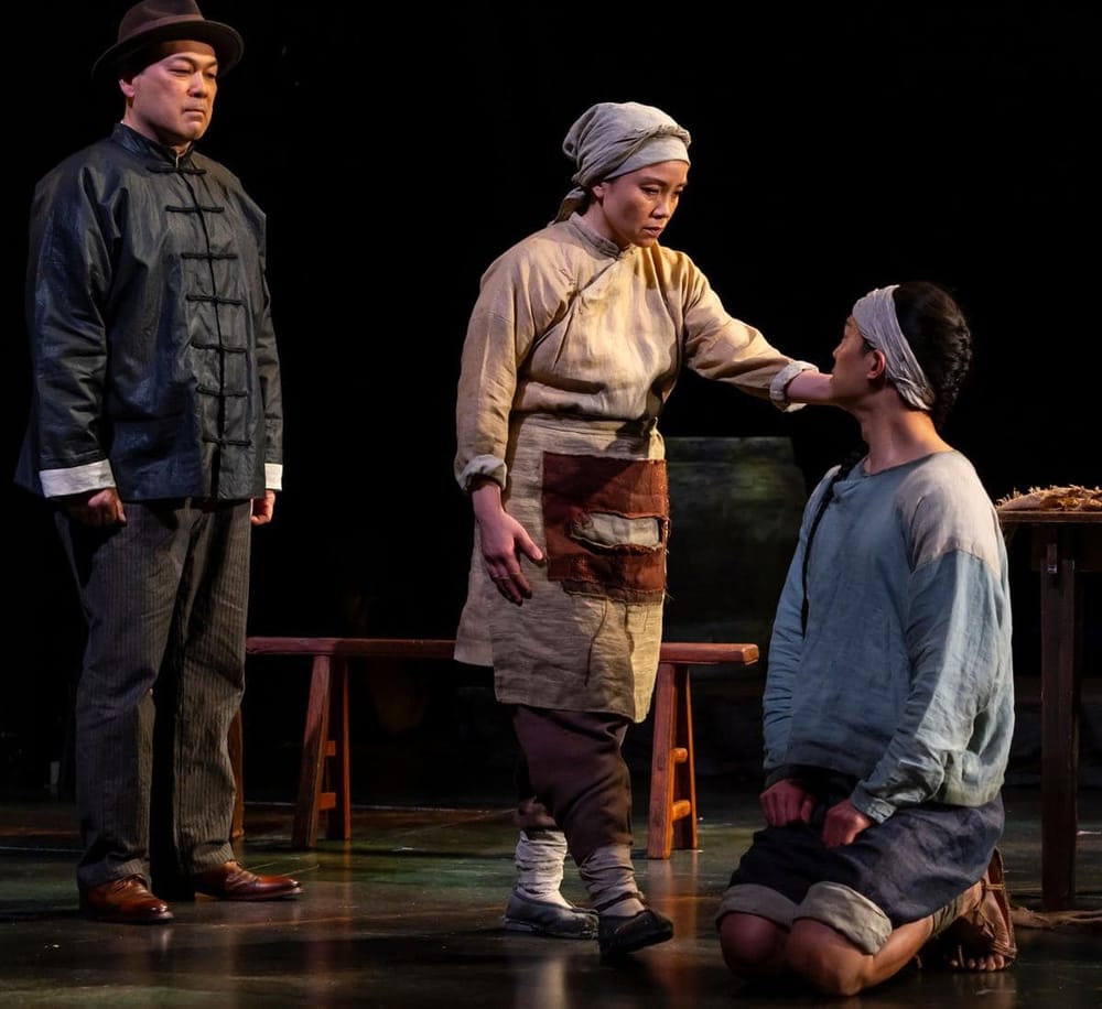 A dramatic scene from a stage play featuring three actors in traditional costumes, emphasizing cultural storytelling.