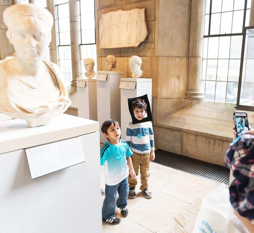 Ancient sculptures exhibit at museum, children enjoying educational museum tour experience.