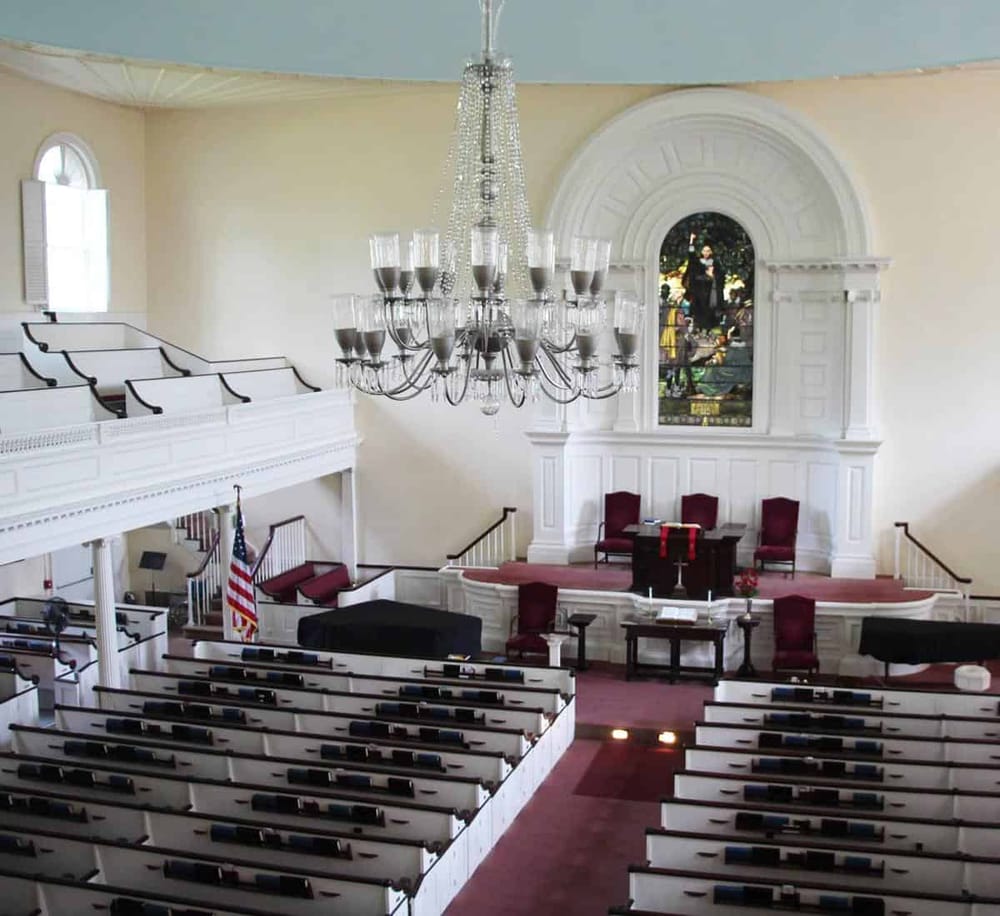Spacious church interior with altar, stained glass window, and seating, ideal for worship and community events.