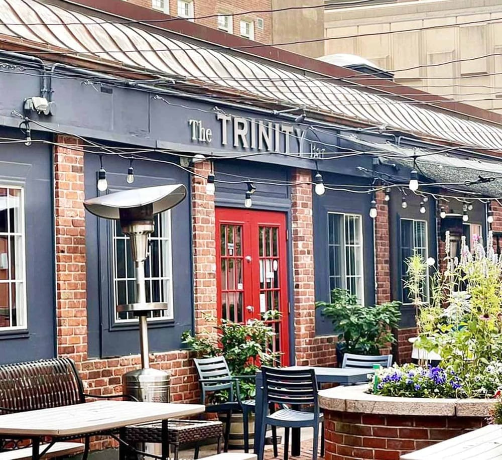 Cozy outdoor patio at The Trinity pub with string lights and seating, perfect for relaxing and socializing.