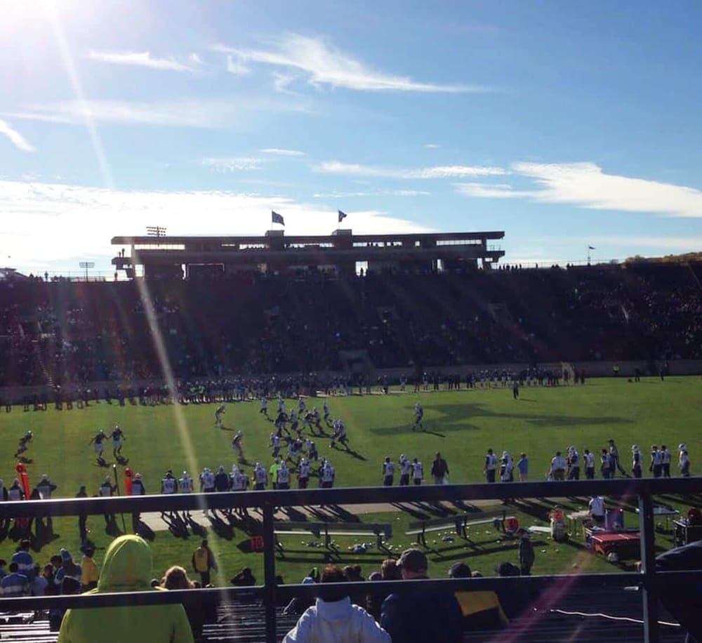 1. American football game at a stadium during sunny day with spectators and players.