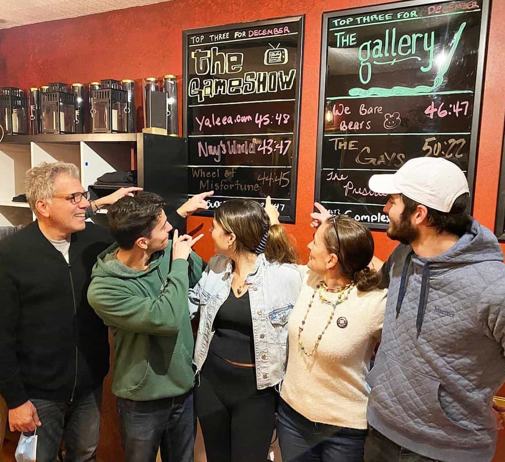 Aliased: Group of friends discussing top video game choices at a gaming bar with blackboards.