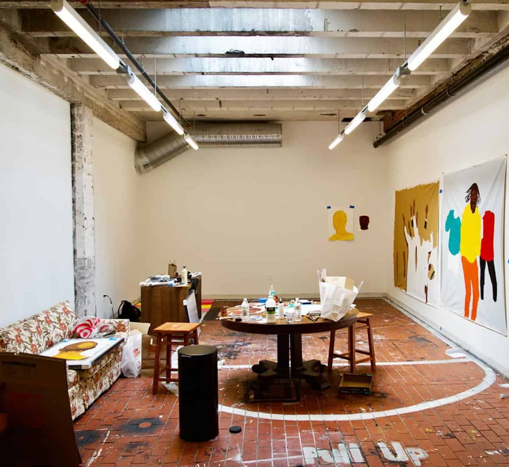 Colorful modern art studio with paintings on the walls and art supplies on the table, ideal for creative visual projects.