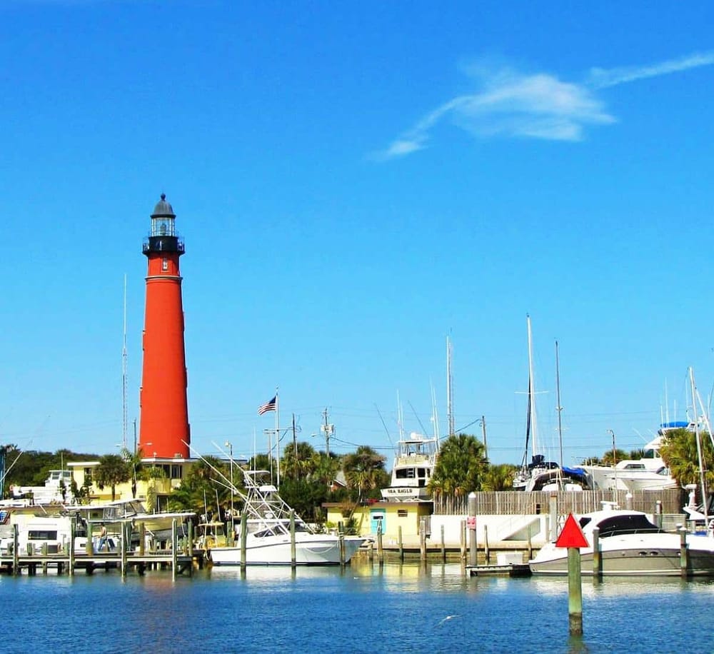Lighthouse and marina in coastal town for navigation and travel guidance.