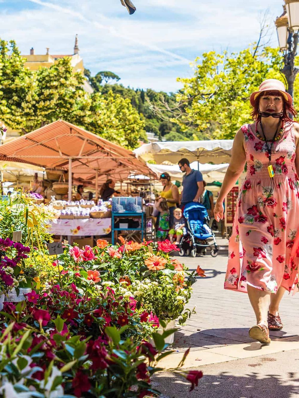 Vibrant outdoor marketplace with flowers, shoppers, and scenic background, ideal for exploring local vendors.