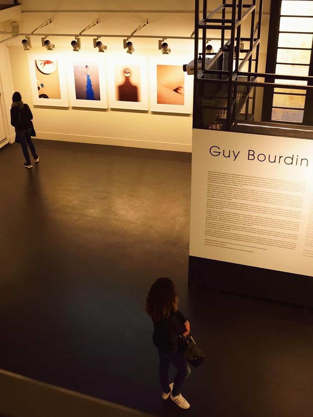 Colorful abstract art exhibit at QuestForDirections gallery with attentive visitors.