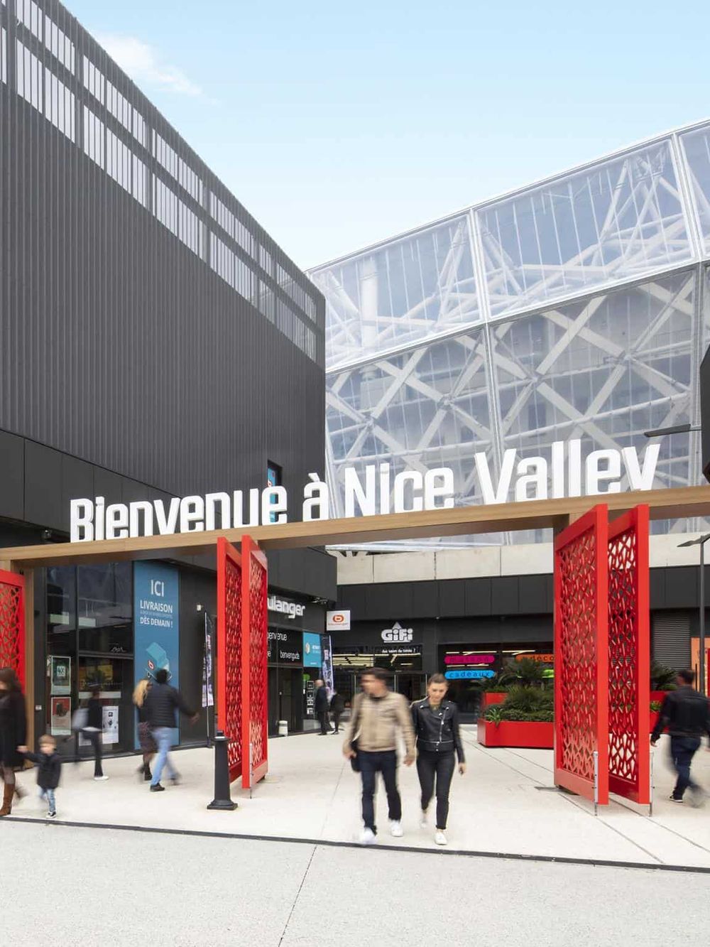 Modern shopping mall entrance in Nice Valley with signage and visitors.