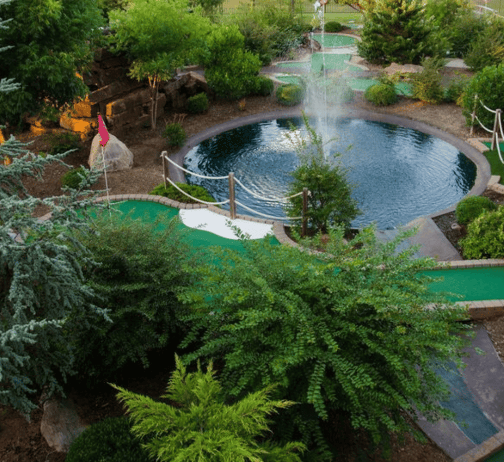 Lush landscaped miniature golf course with water features and greenery for family fun.