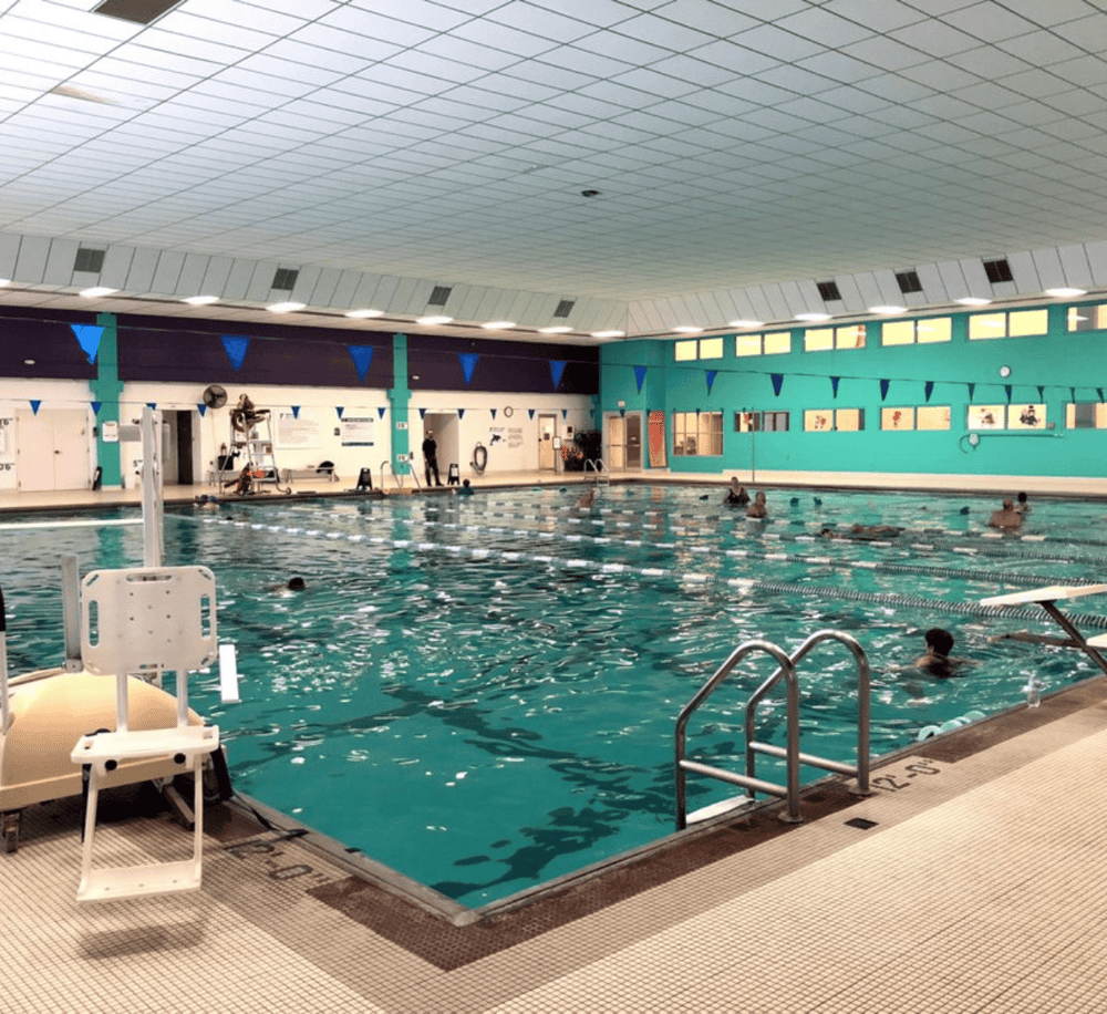 Indoor swimming pool at Quest For Directions facility with swimmers enjoying the water.