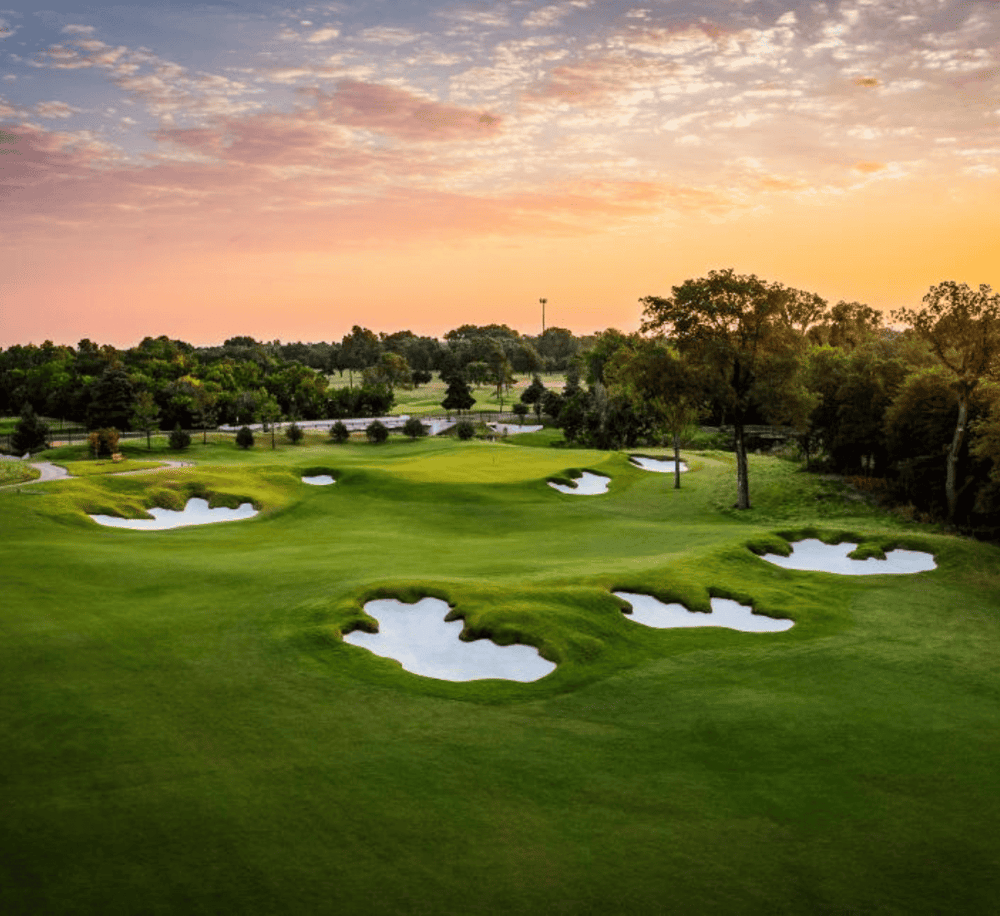 Luxurious golf course at sunset with sand traps and lush green fairways, perfect for golf lovers.